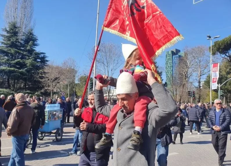 Gjyshi me mbesën e vogël me qeleshe dhe flamurin kuq e zi në pr otestë